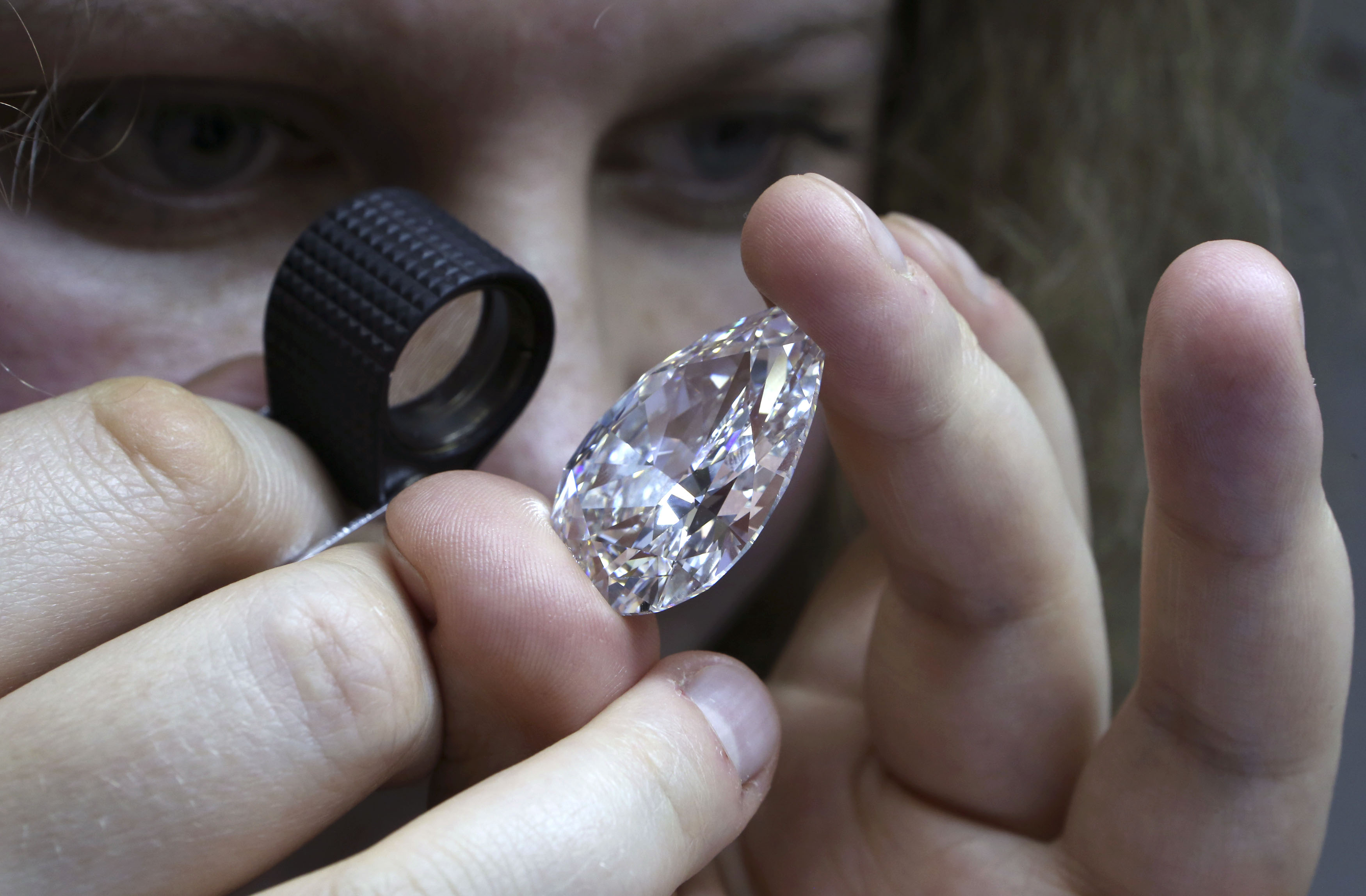 An employee inspects a diamond during a demonstration at the lapidary enterprise "Diamonds ALROSA", owned by Alrosa company, in Moscow