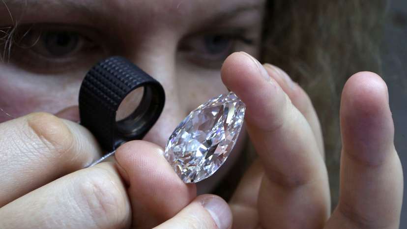 An employee inspects a diamond during a demonstration at the lapidary enterprise "Diamonds ALROSA", owned by Alrosa company, in Moscow