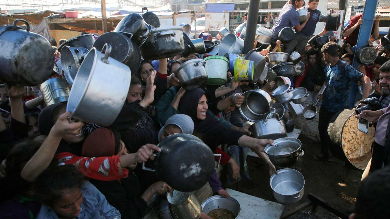 FILE PHOTO: Palestinians gather to receive food cooked by a charity kitchen, in Khan Younis