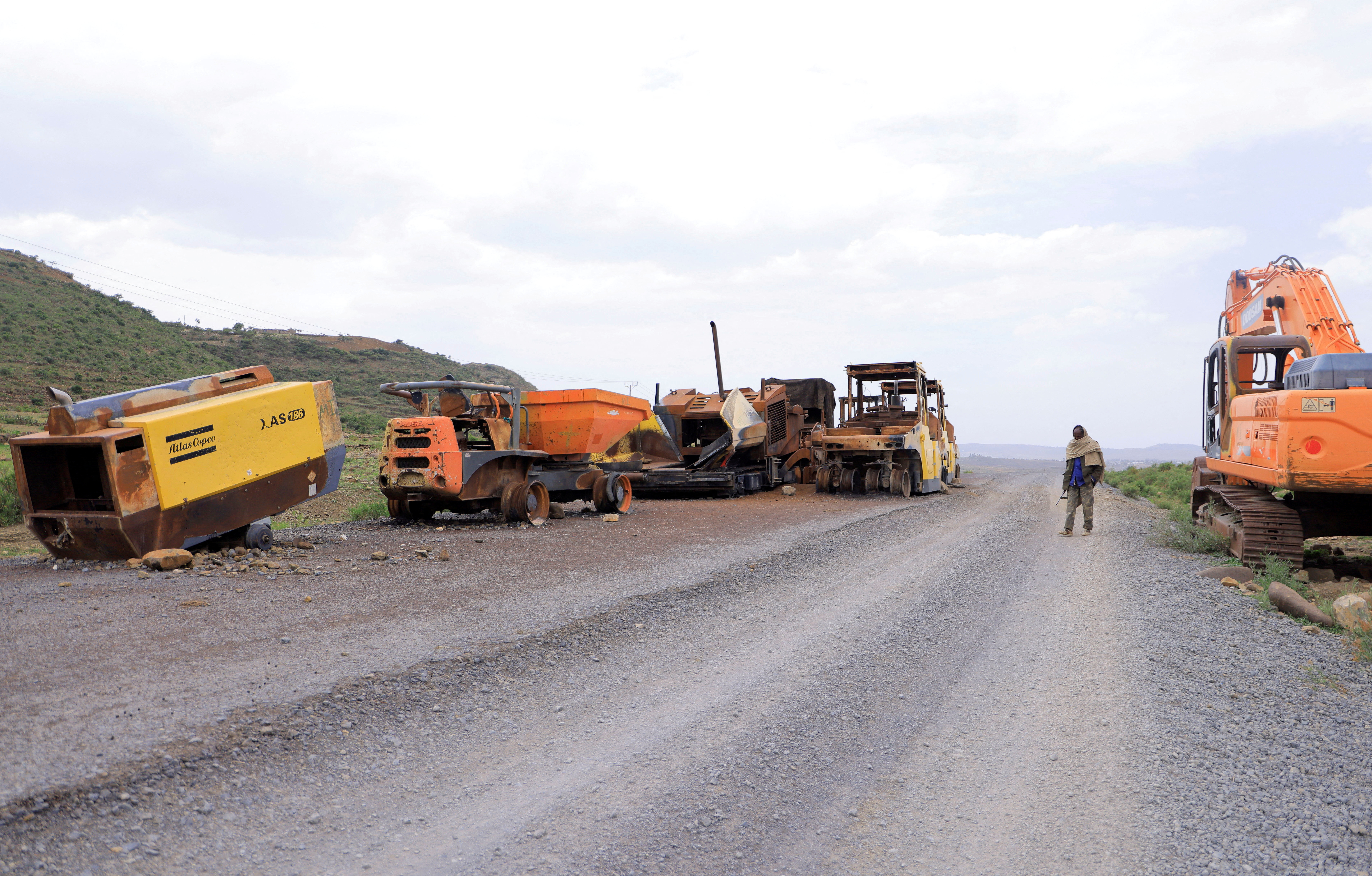 FILE PHOTO: A Tigrayan Militia member stands next to destroyed construction machineries during the fighting between the TPLF and ENDF on the outskirt of Samre town, Tigray Region