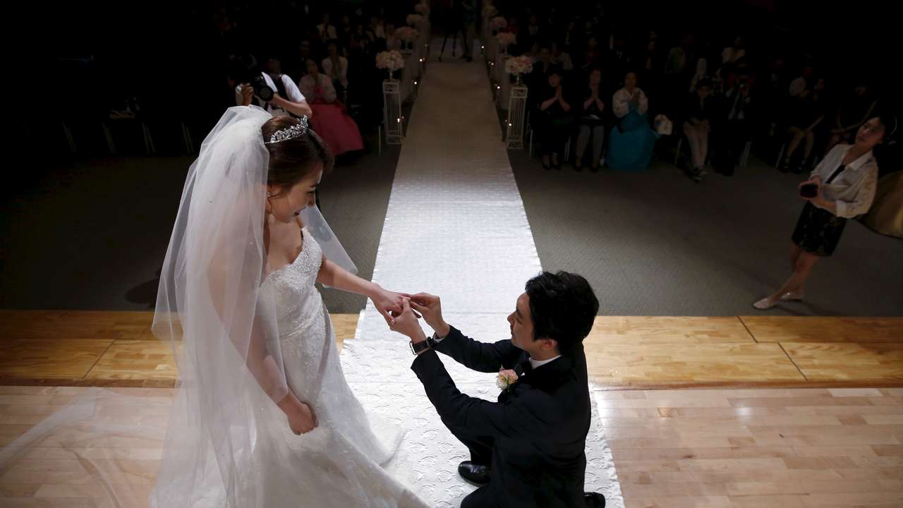 Groom puts a wedding ring on his bride's finger during a wedding ceremony at a budget wedding hall at the National Library of Korea in Seoul, South Korea