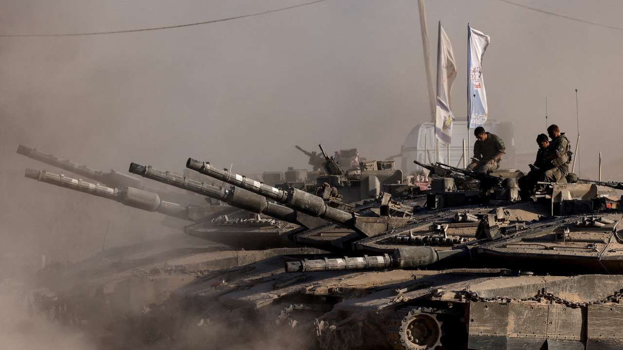 Israeli soldiers sit on top of tanks at the Israel-Gaza border
