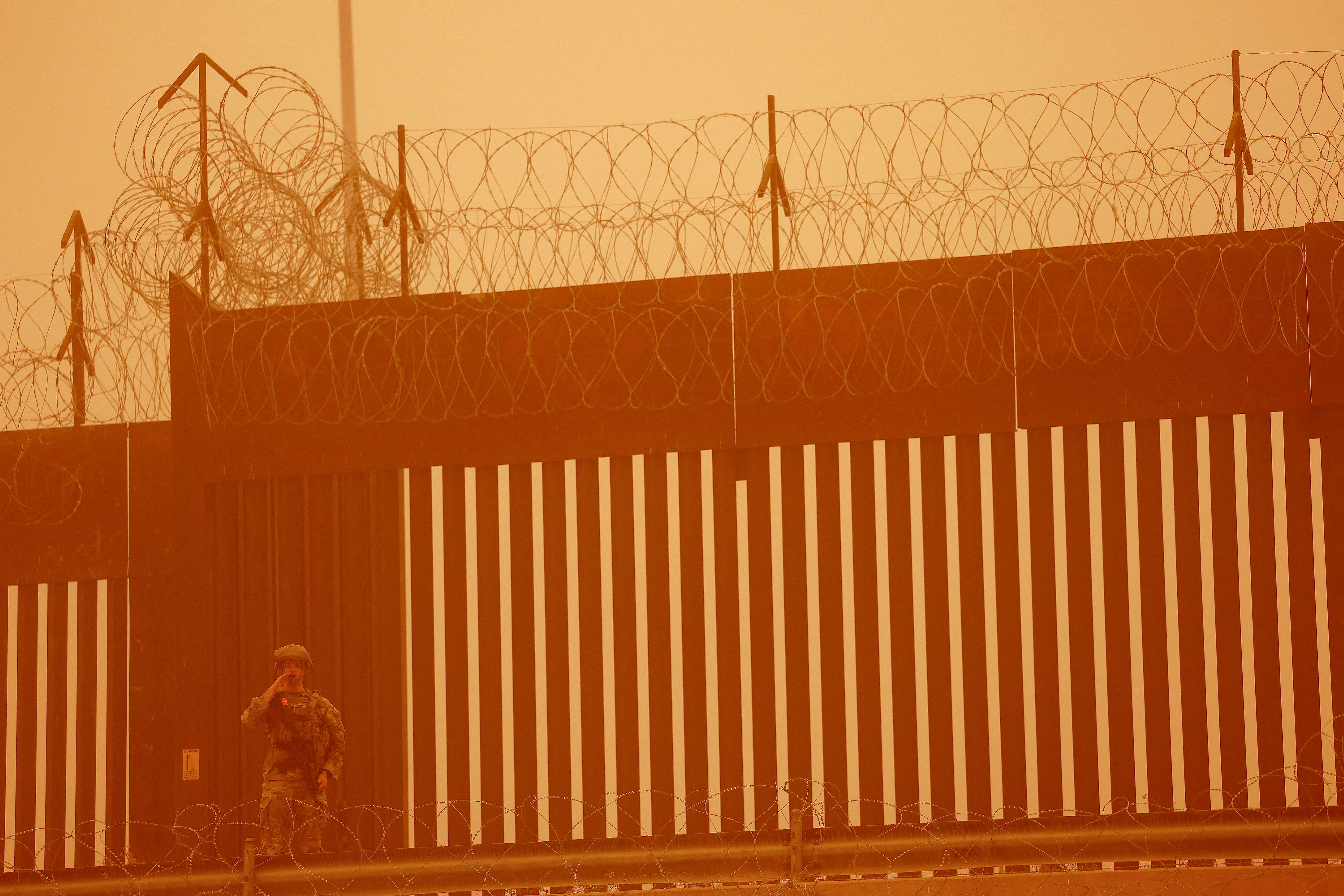 FILE PHOTO: A Texas National Guard soldier stands near the wall on the border between Mexico and U.S. during a sandstorm