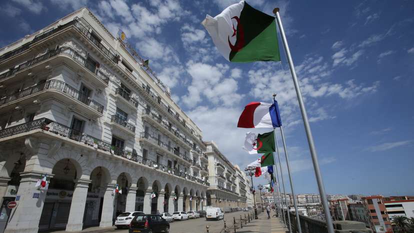 FILE PHOTO: Vehicles pass Algerian and French flags, ahead of the arrival of French President Emmanuel Macron in Algiers