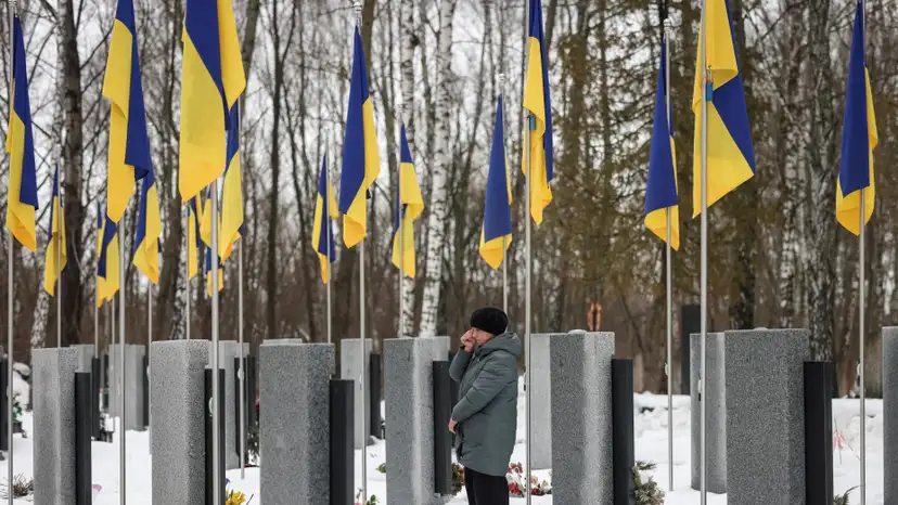 A woman reacts as she stands in front of a grave at a local cemetery, as she pays tribute to the victims of the Russian attack on Ukraine