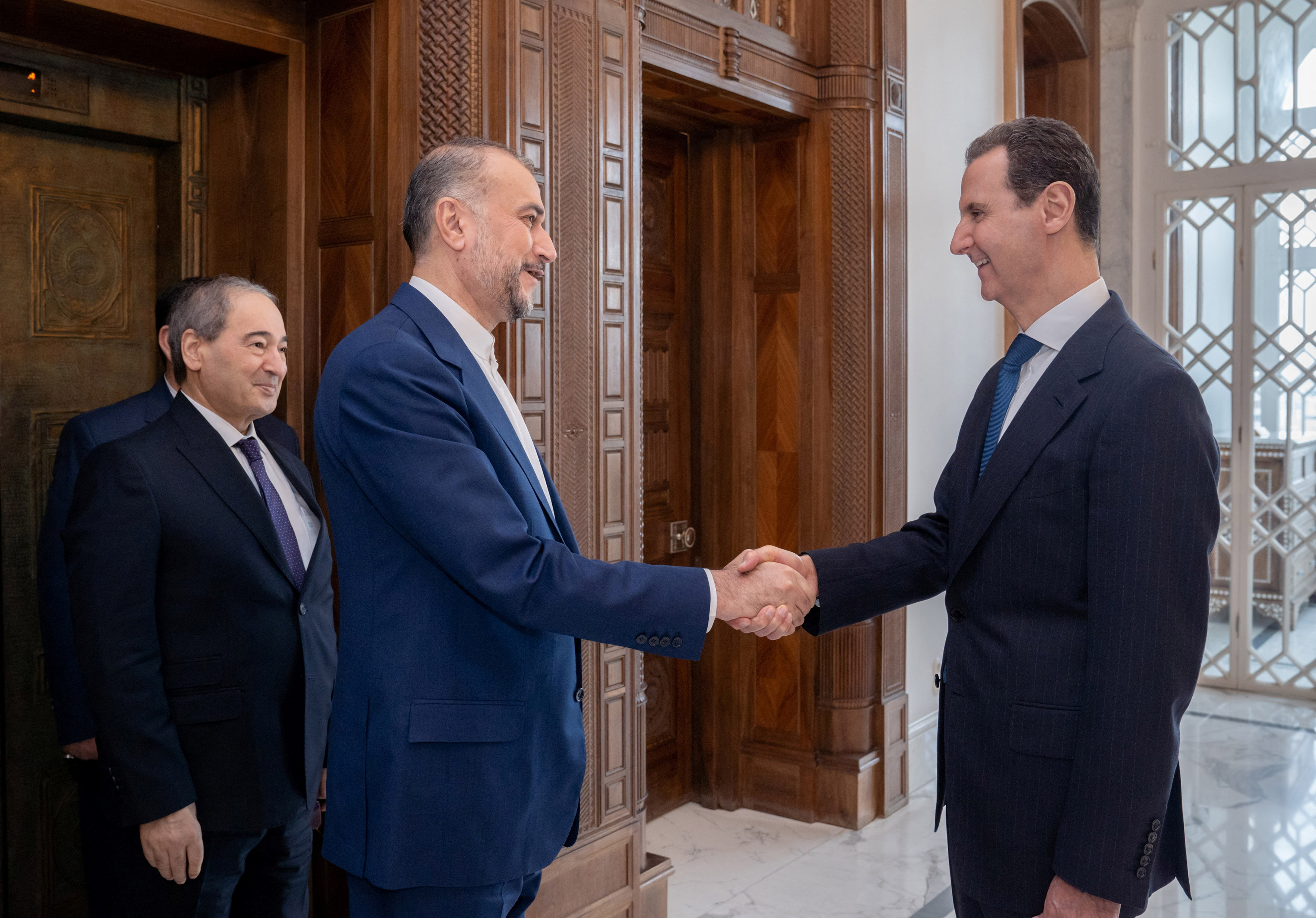 Syria's President Bashar al-Assad shakes hands with Iran's Foreign Minister Hossein Amirabdollahian in Damascus