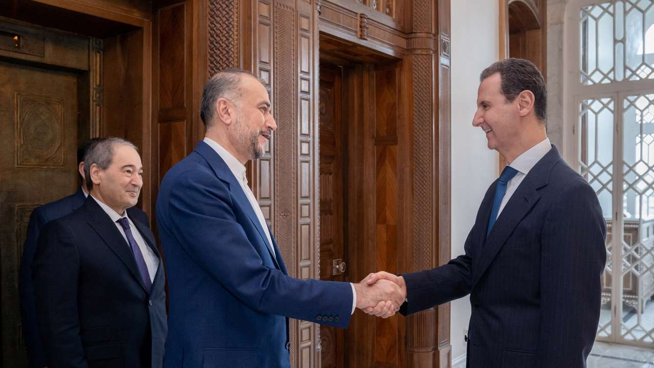 Syria's President Bashar al-Assad shakes hands with Iran's Foreign Minister Hossein Amirabdollahian in Damascus