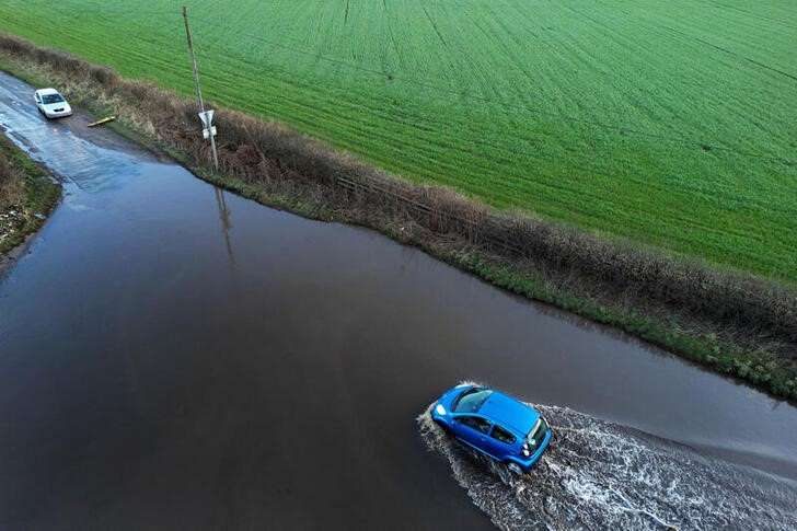 A car drives through flood water after heavy rain from Storm Isha