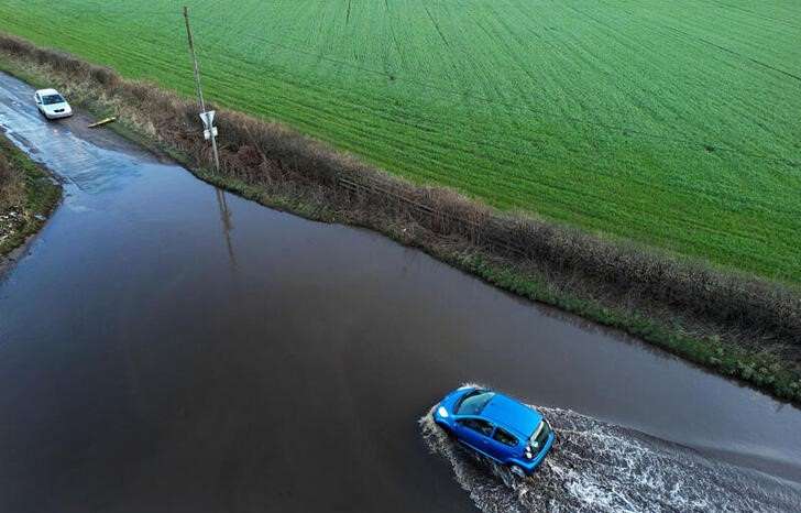 A car drives through flood water after heavy rain from Storm Isha