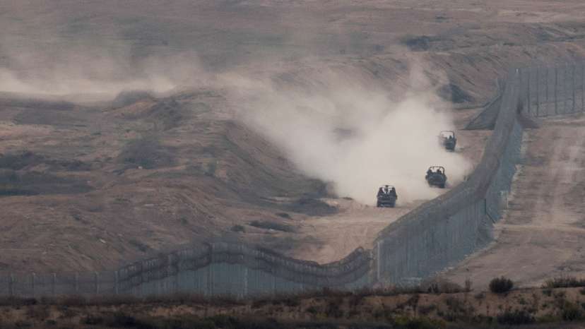 FILE PHOTO: Military vehicles manoeuvre next to a fence, as seen from the Israeli side of the border with Gaza