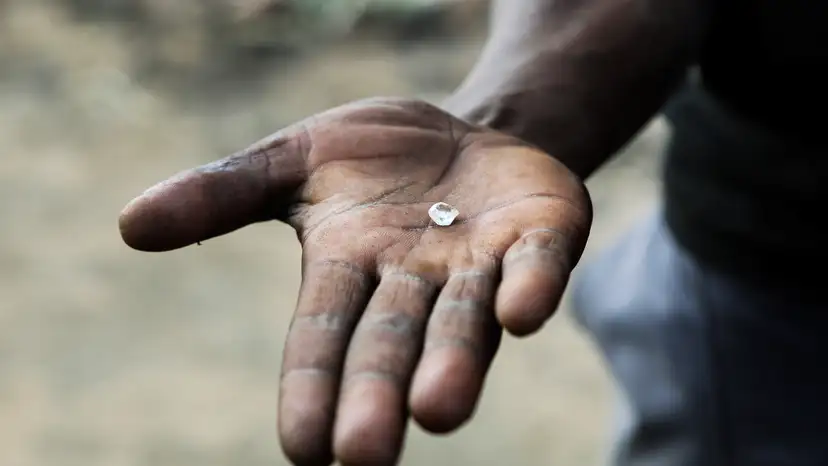 An artisanal miner holds an uncut diamond in his hand in Kimberley