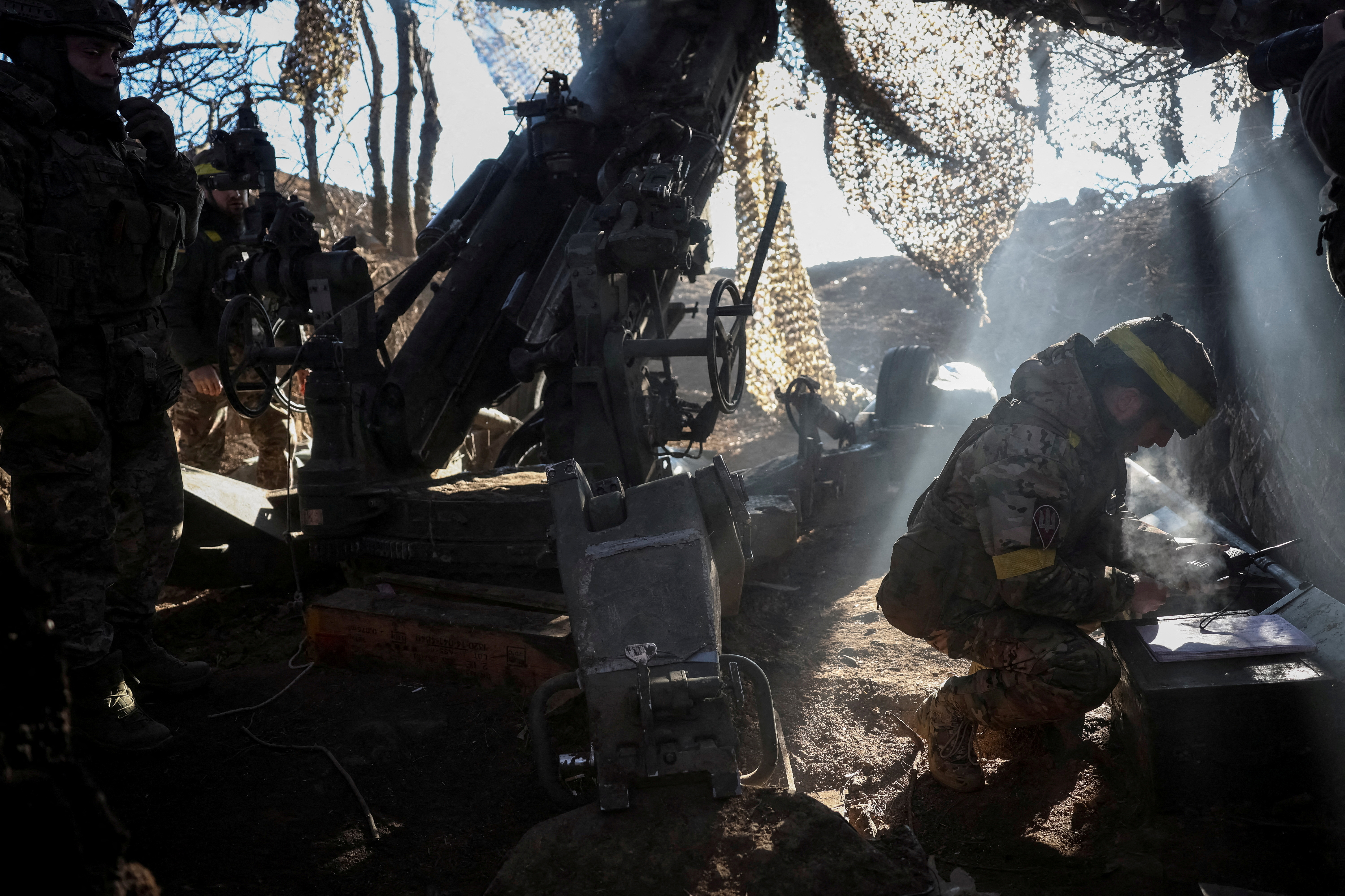 FILE PHOTO: Servicemen fire a howitzer towards Russian troops at a position in a front line in Donetsk region