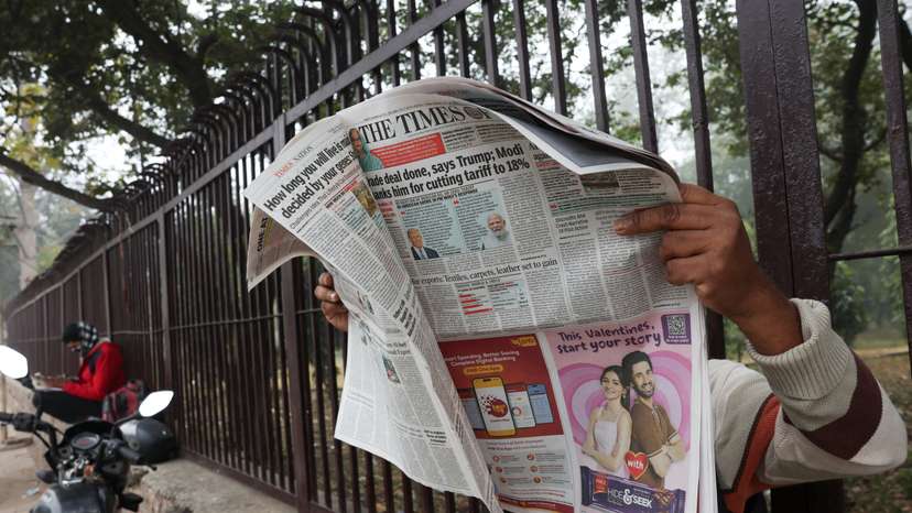 A man reads the latest edition of The Times of India newspaper, with the story on U.S. tariffs