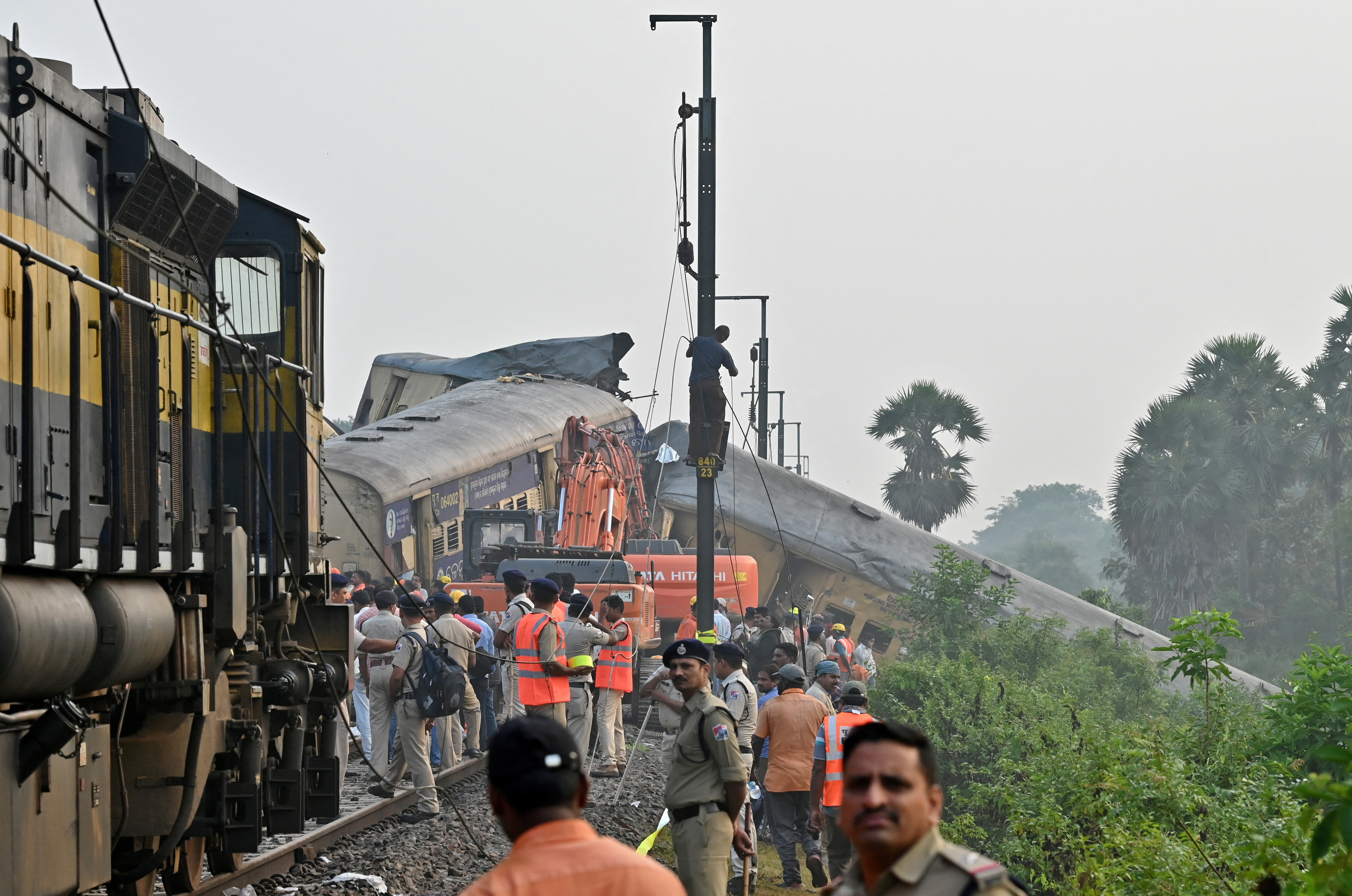 Rescue workers and police officials stand next to damaged coaches following a collision between two passenger trains in Vizianagaram