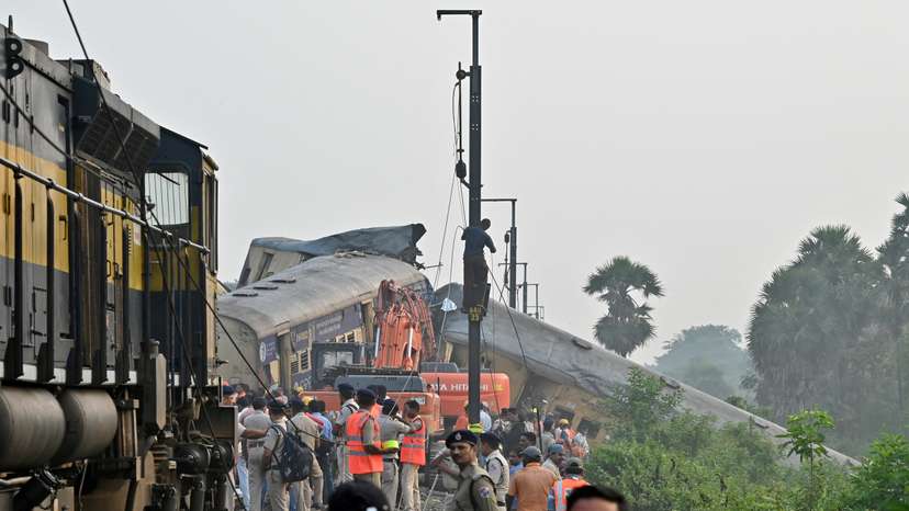 Rescue workers and police officials stand next to damaged coaches following a collision between two passenger trains in Vizianagaram