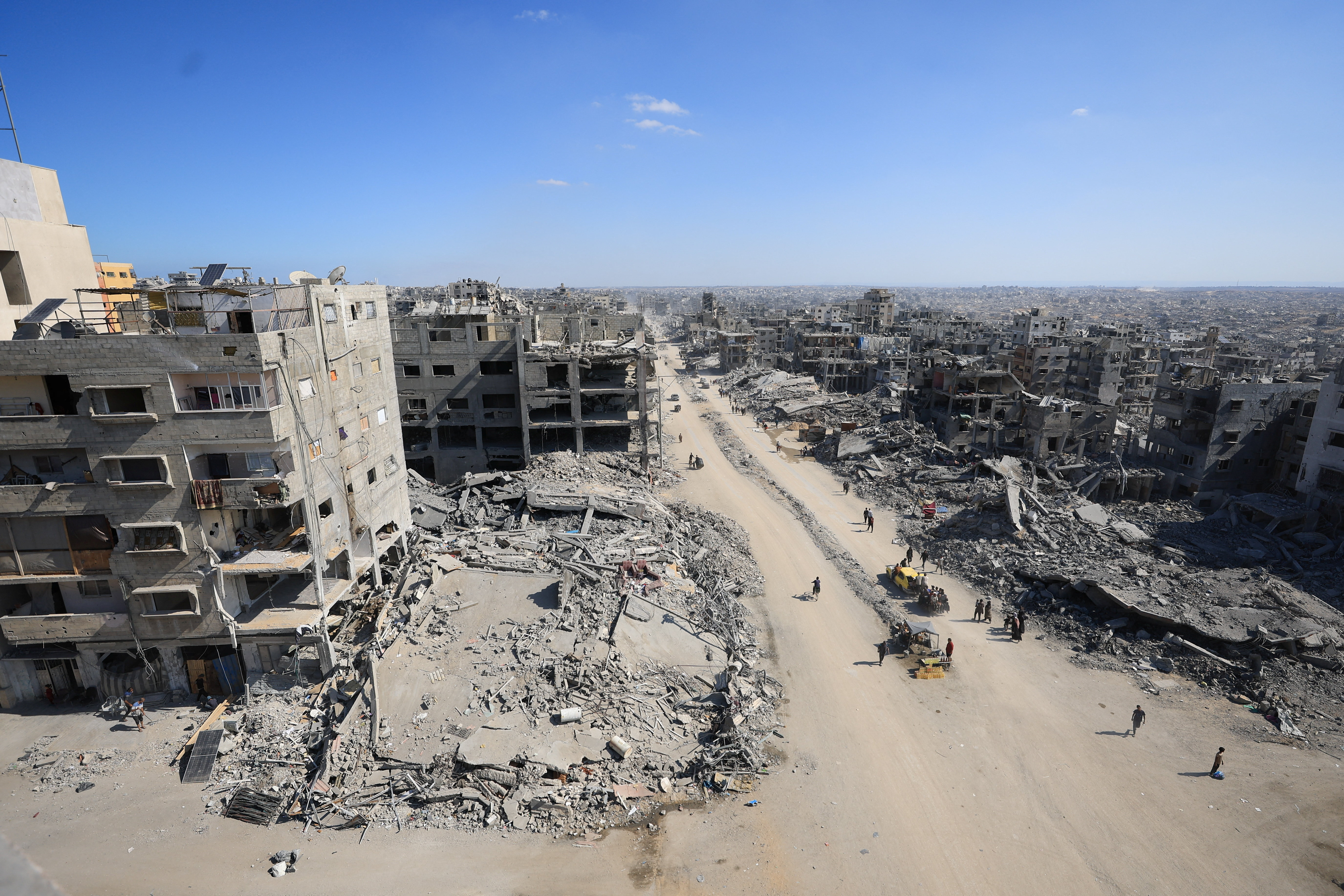 Palestinians walk past the rubble of destroyed buildings, in Gaza City
