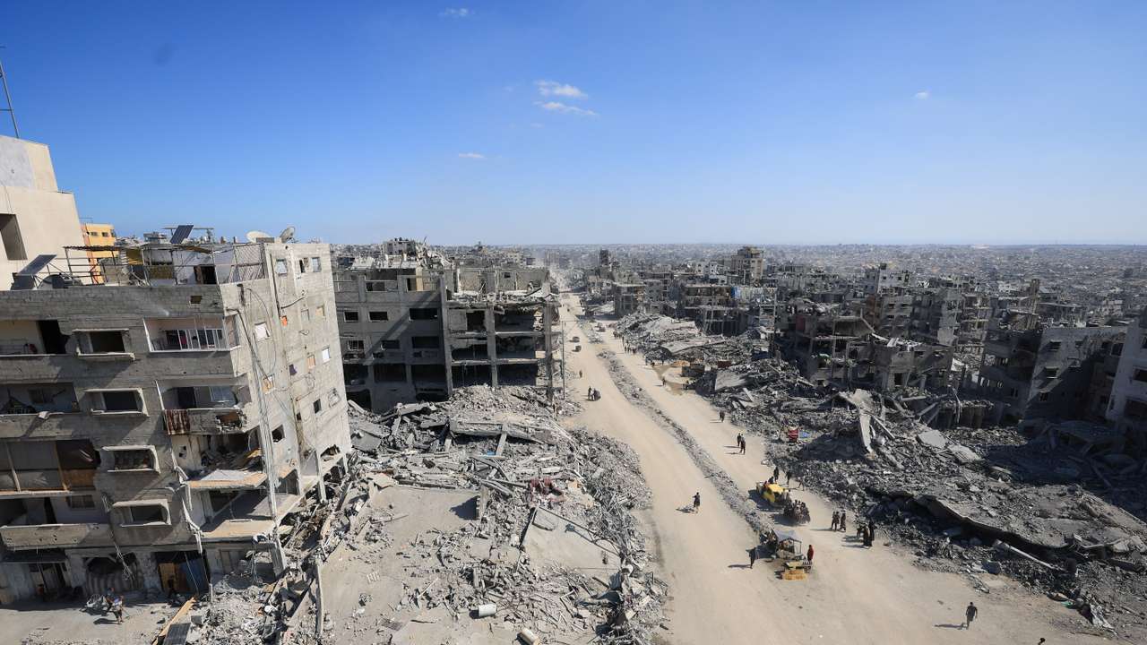 Palestinians walk past the rubble of destroyed buildings, in Gaza City