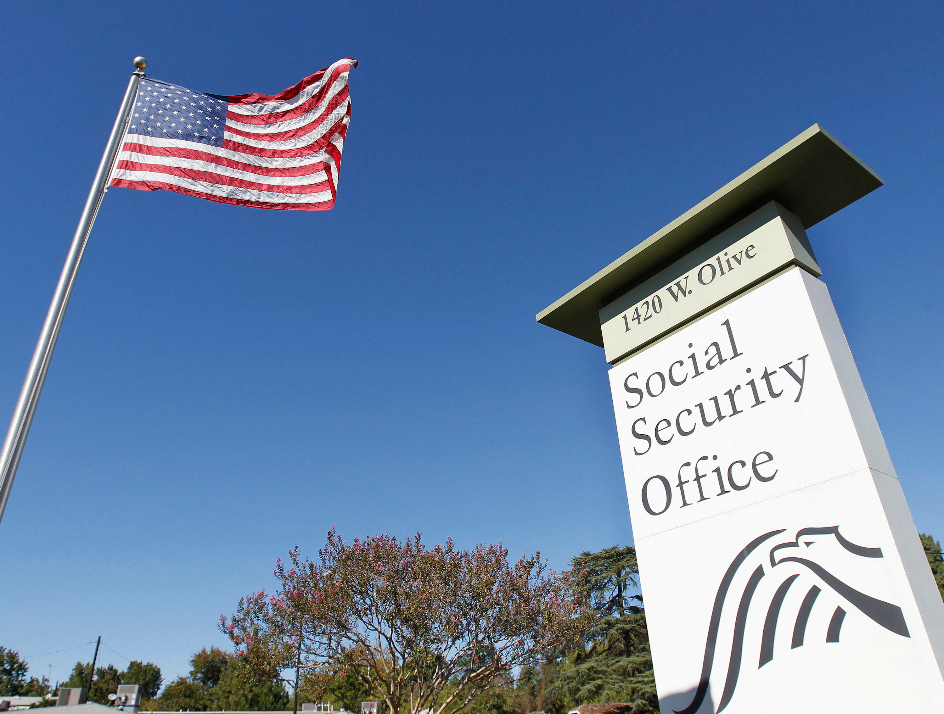 FILE PHOTO: An American flag flutters in the wind next to signage for a U.S. Social Security Administration office in Burbank