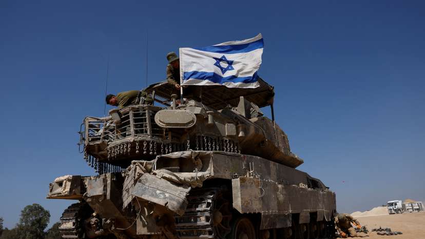 FILE PHOTO: Israeli soldiers mount a flag on a military vehicle near the Israel-Gaza border