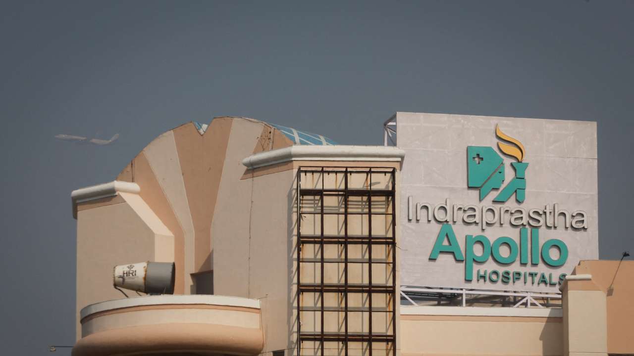 An airplane flies past an Apollo Hospital building in New Delhi