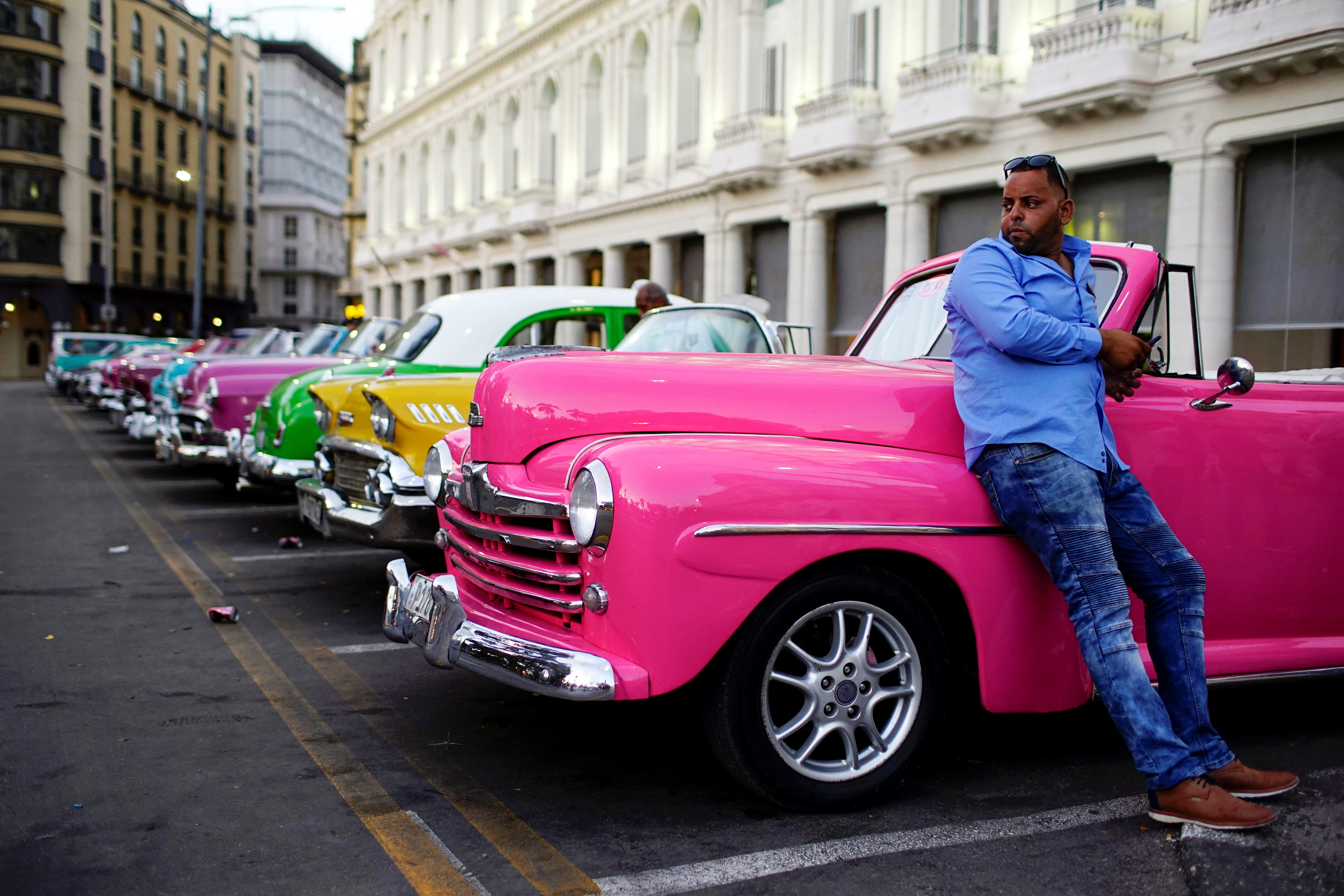 Driver Giovani Bernati waits for tourists beside vintage cars used as taxi in Havana