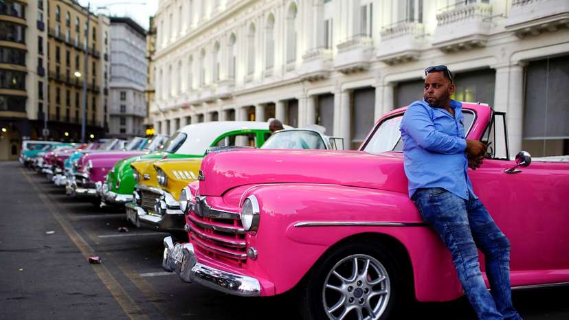 Driver Giovani Bernati waits for tourists beside vintage cars used as taxi in Havana