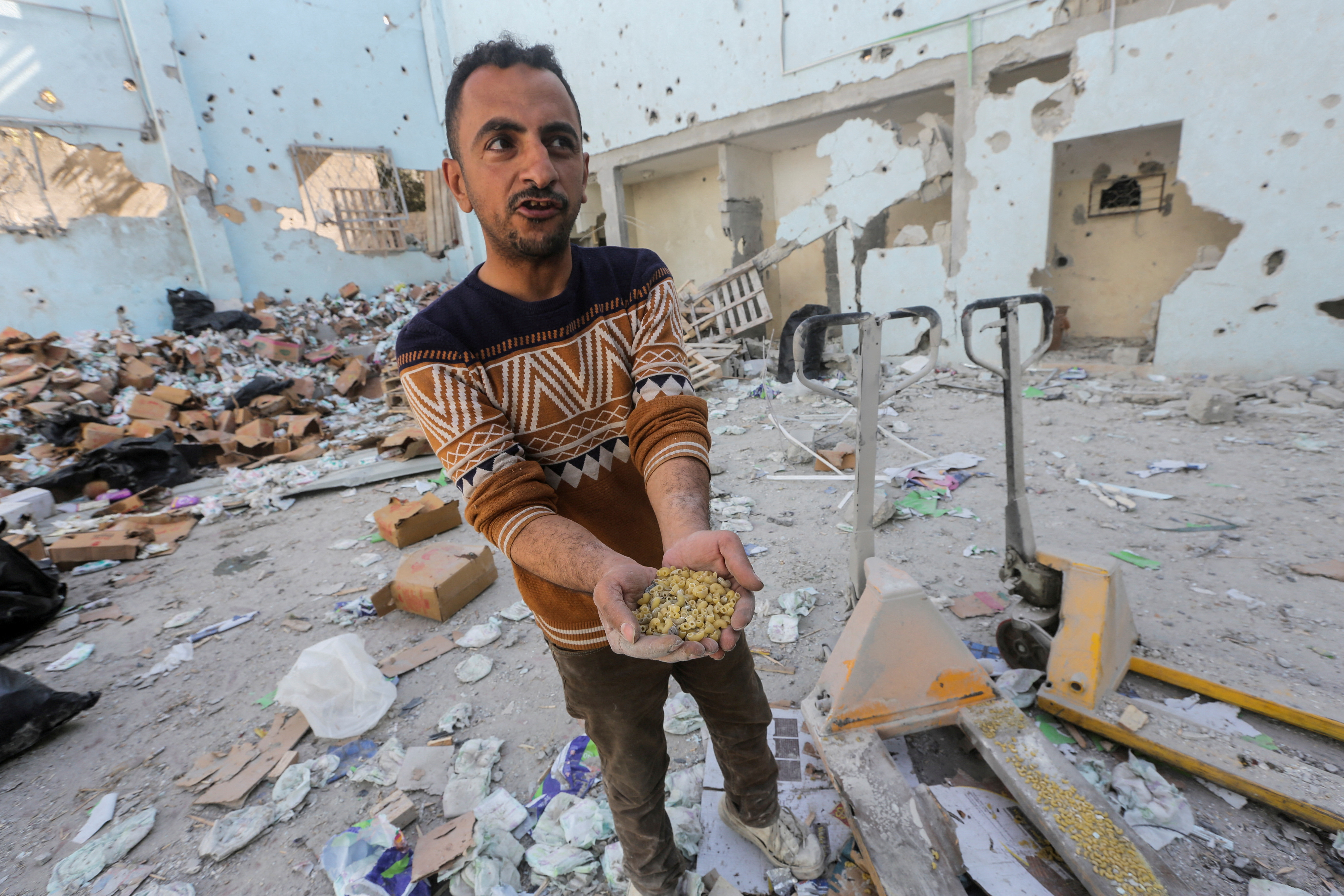 Palestinians inspect the site of an Israeli strike on an aid warehouse, in Al-Nuseirat refugee camp