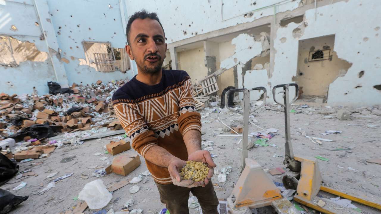 Palestinians inspect the site of an Israeli strike on an aid warehouse, in Al-Nuseirat refugee camp