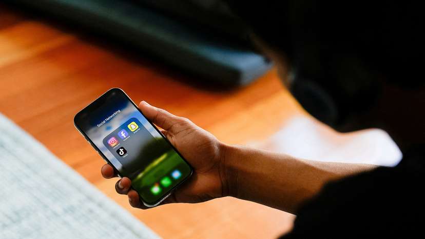 High school student poses with his mobile phone showing social media applications in Melbourne