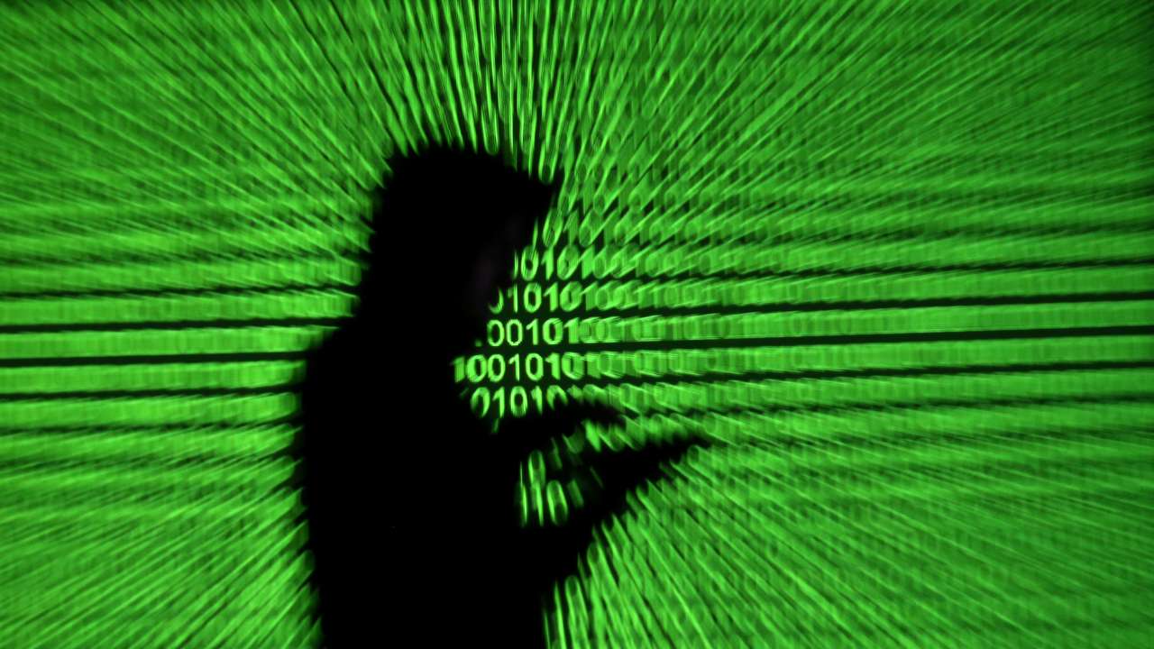 Silhouette of mobile device user is seen next to a screen projection of binary code are seen in this picture illustration