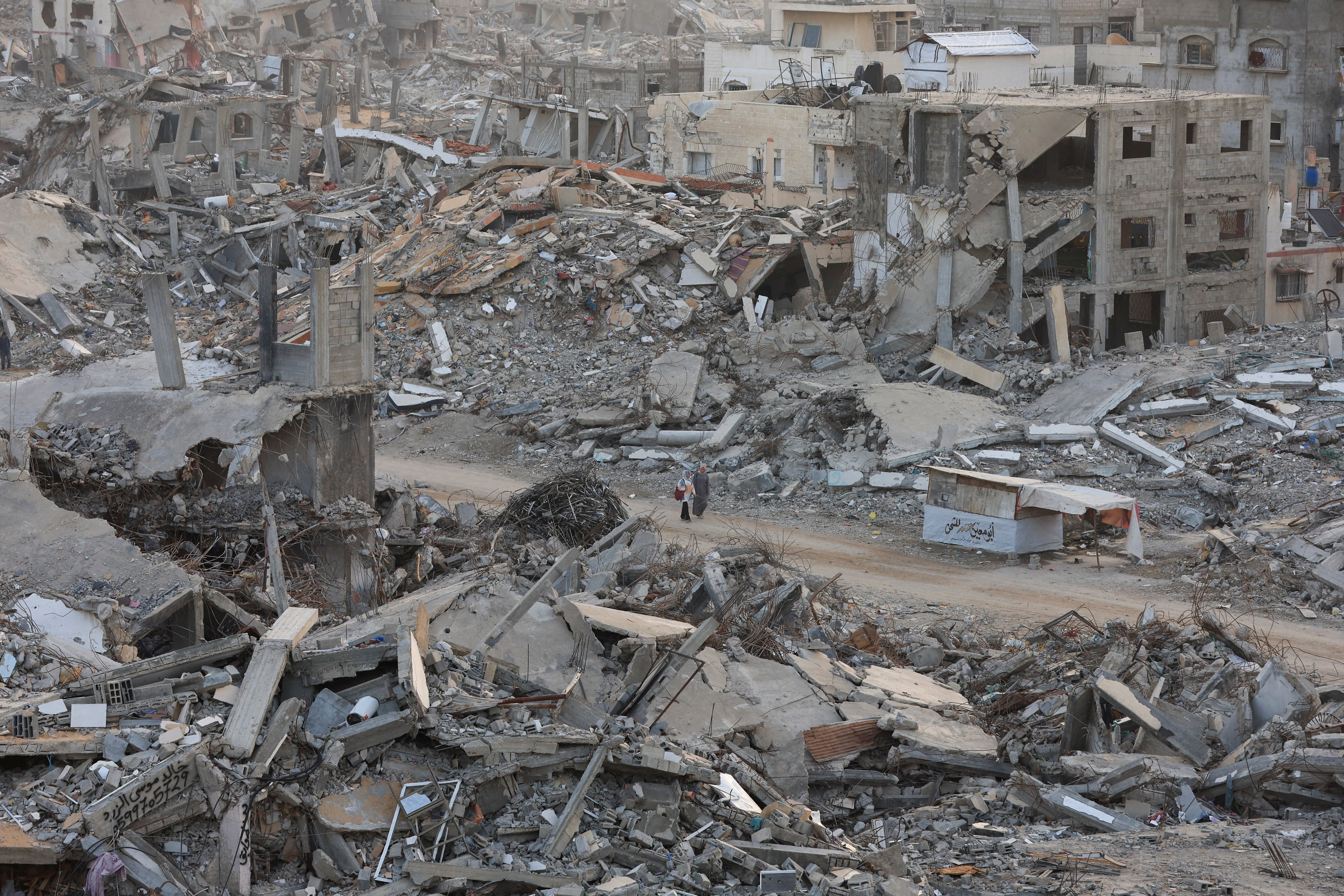 Palestinian women walk among piles of rubble and damaged buildings in Gaza City