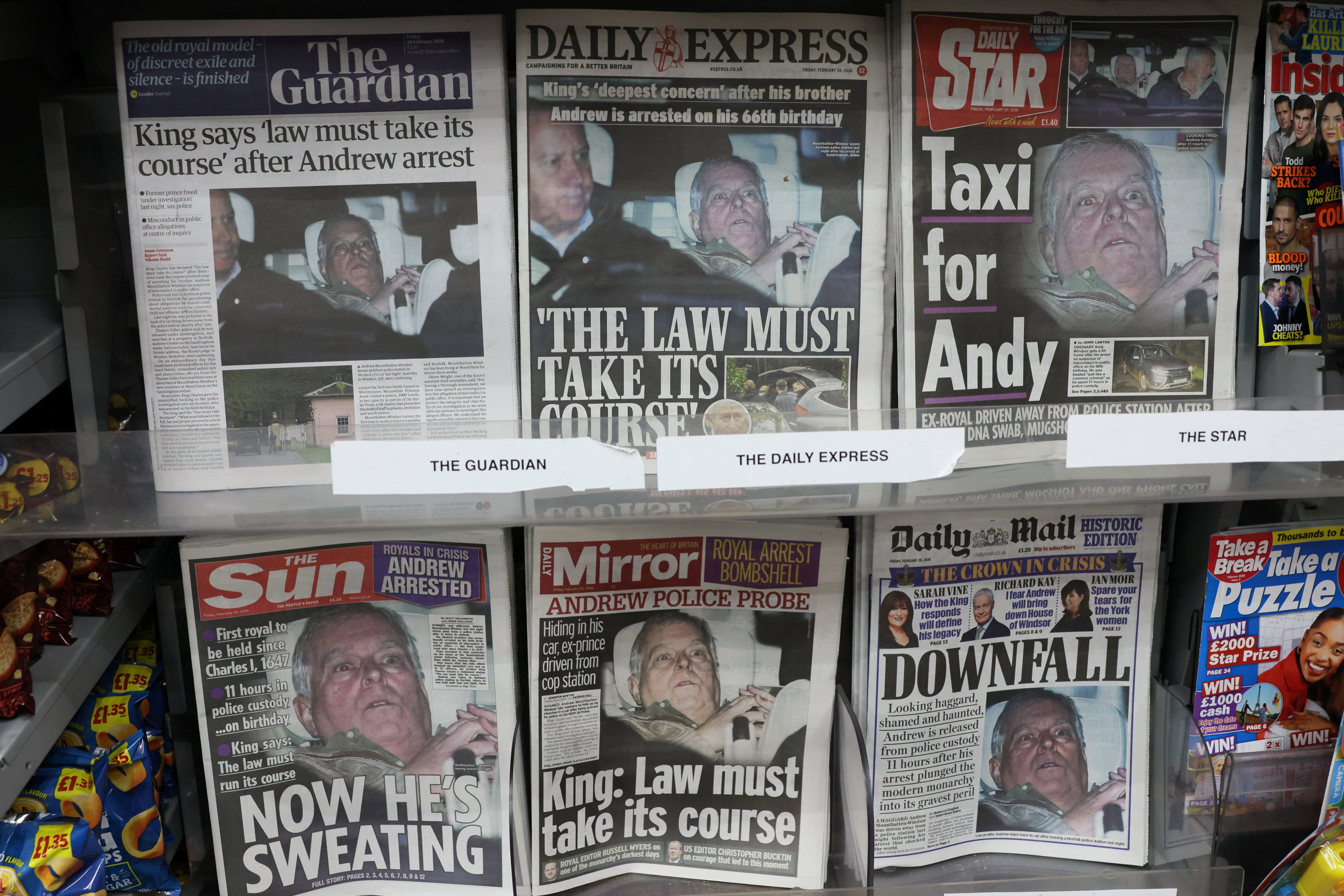 British newspapers, featuring coverage of the arrest of Andrew Mountbatten-Windsor, younger brother of Britain's King Charles, on suspicion of misconduct in public office, sit on display in a newsagent in London