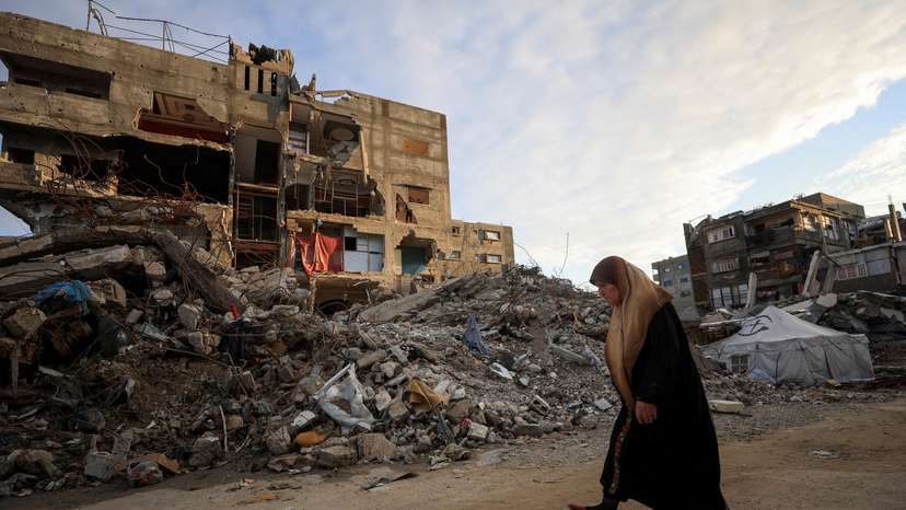 FILE PHOTO: Palestinian woman walks past residential buildings damaged and destroyed during the war, in Gaza City