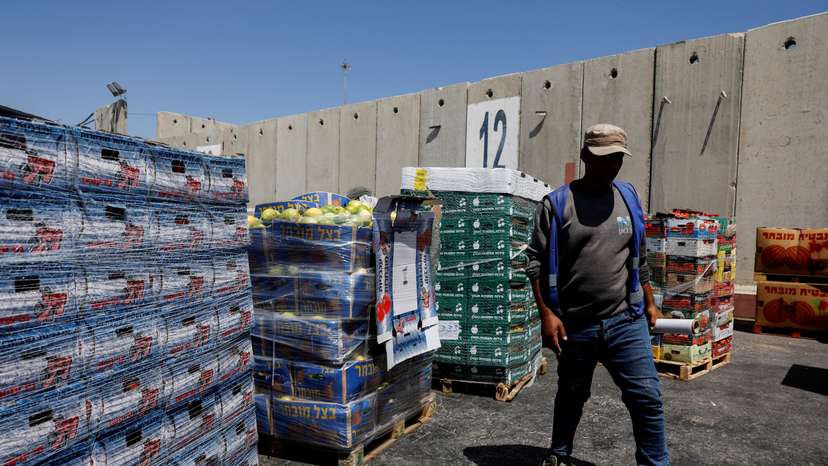 A man walks next to humanitarian aid destined for the Gaza Strip, at the Kerem Shalom crossing