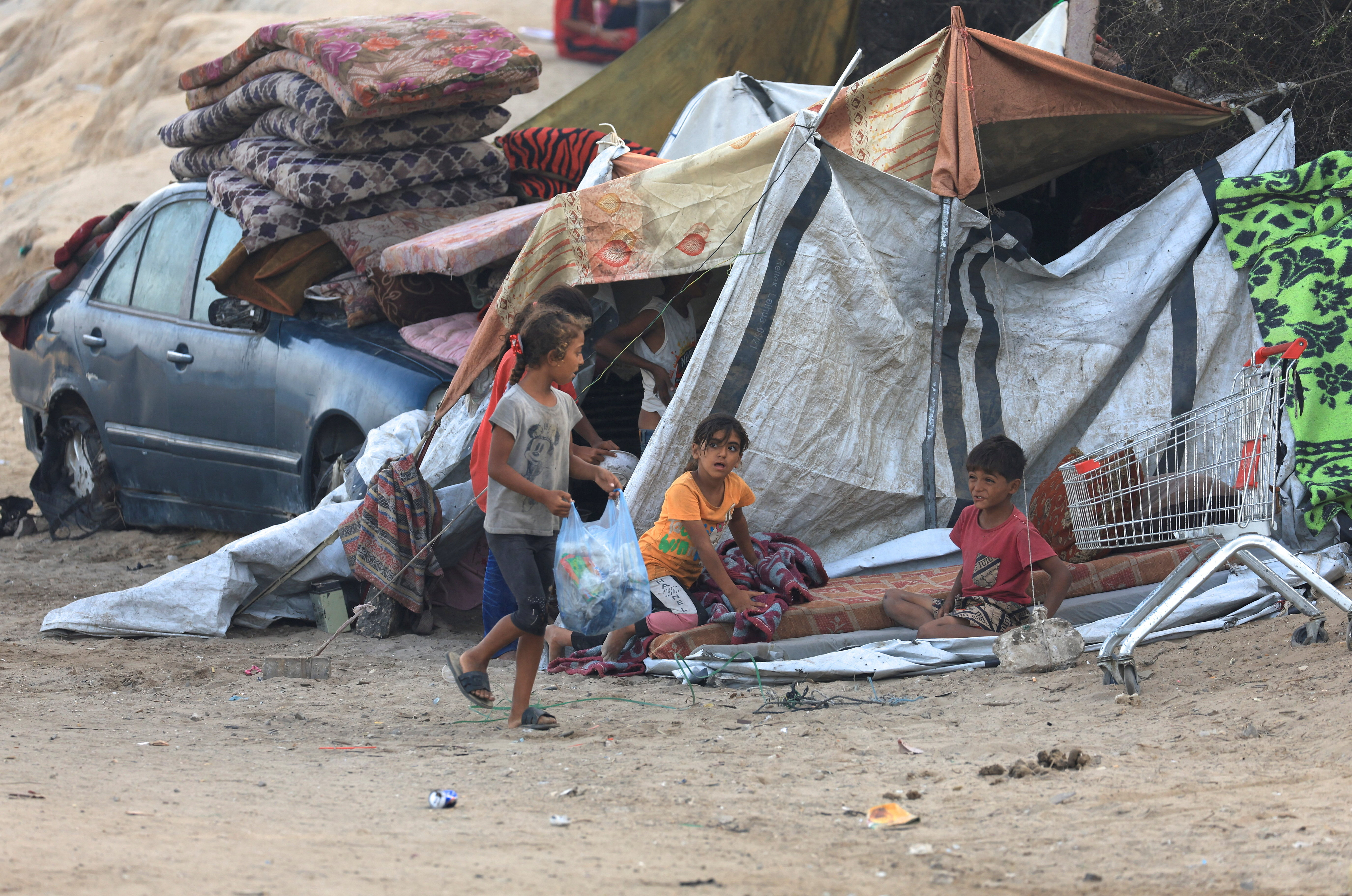 Displaced Palestinians sit next to a tent, after Hamas agreed to release hostages and accept some other terms in a U.S. plan to end the war, in the central Gaza Strip