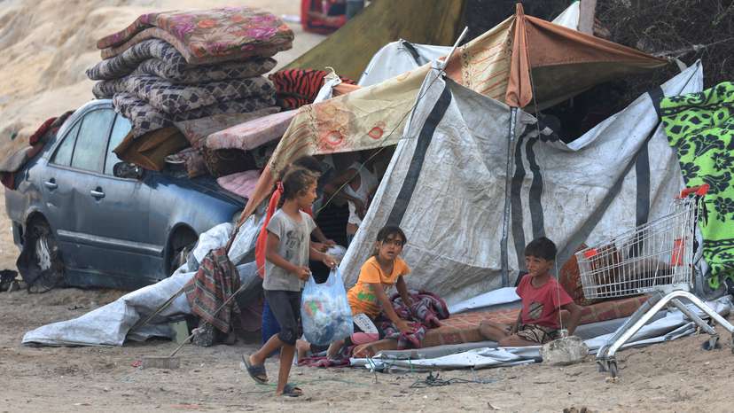 Displaced Palestinians sit next to a tent, after Hamas agreed to release hostages and accept some other terms in a U.S. plan to end the war, in the central Gaza Strip