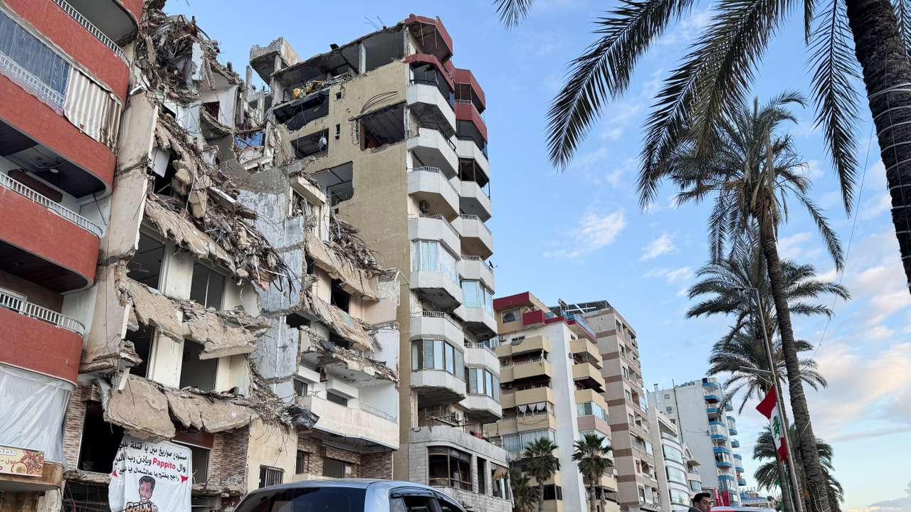 Cars drive past a damaged building near the Corniche, in Tyre