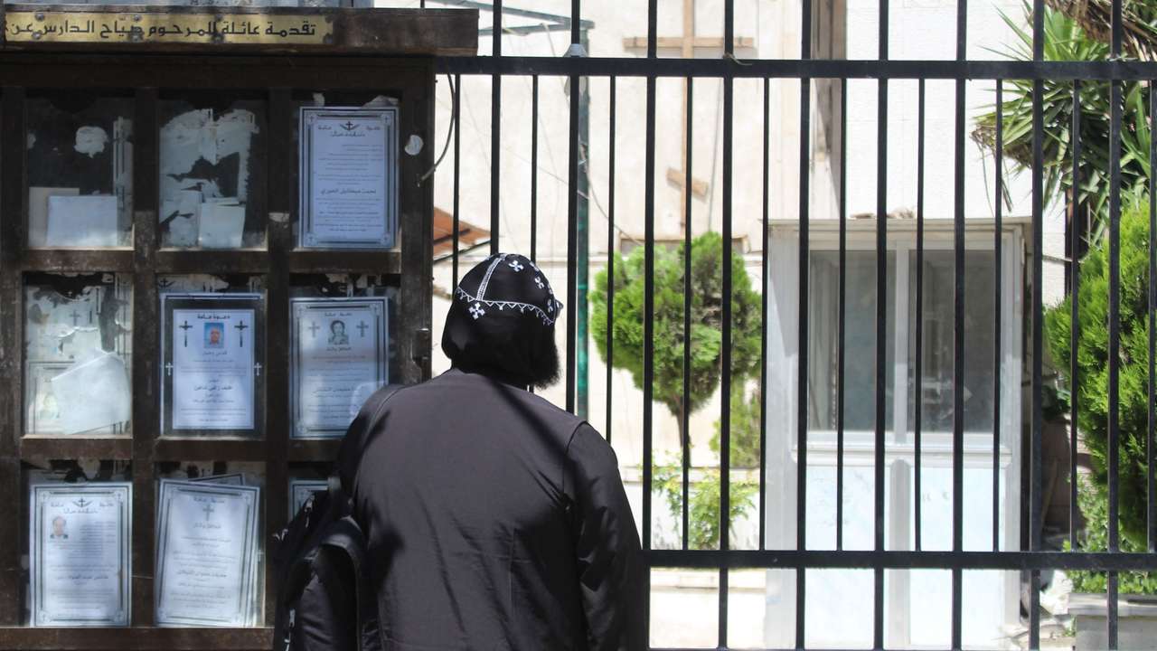 A person stands next to funeral notices at Mar Elias Church in Damascus