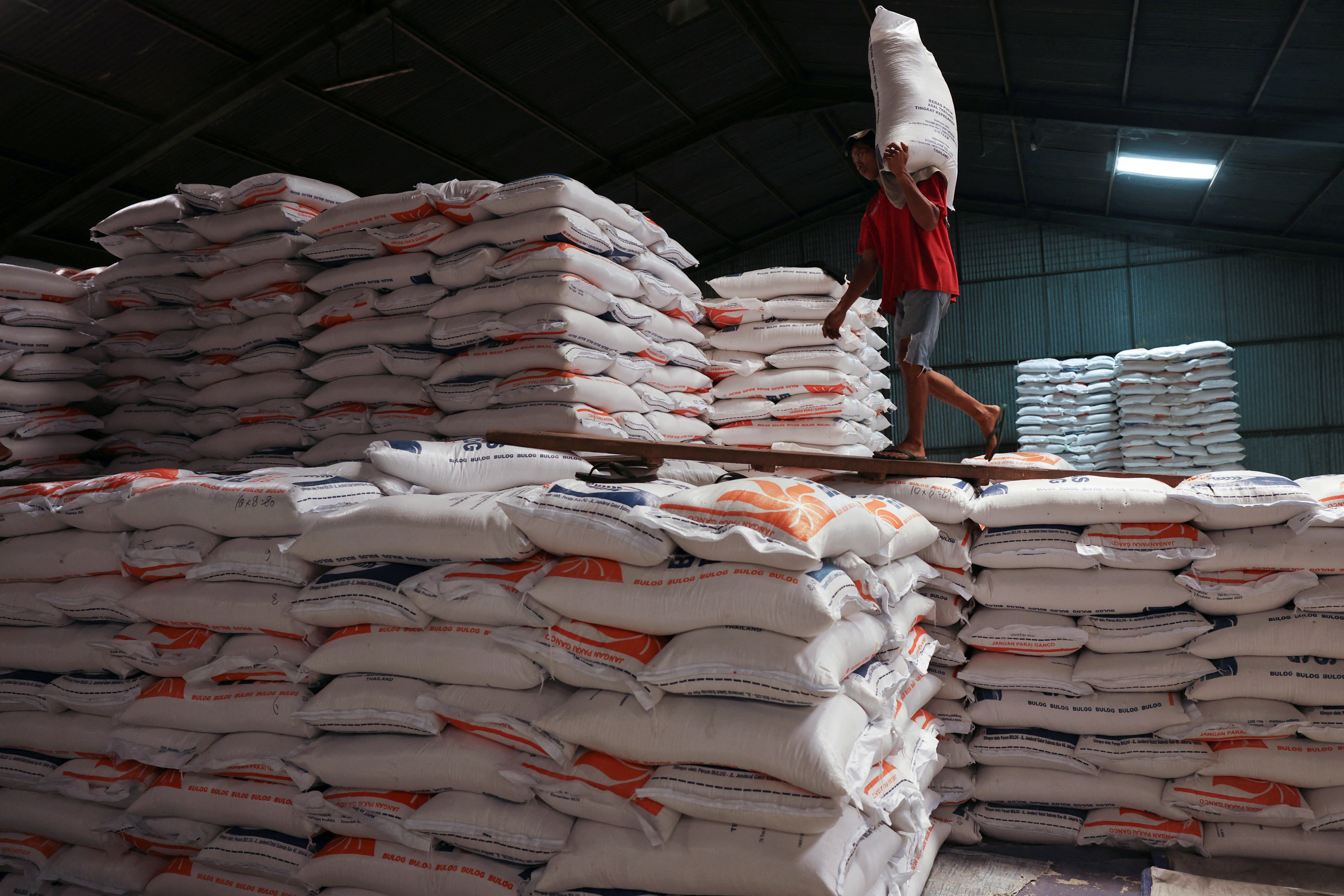 A worker carries a sack of rice at the warehouse in Jakarta