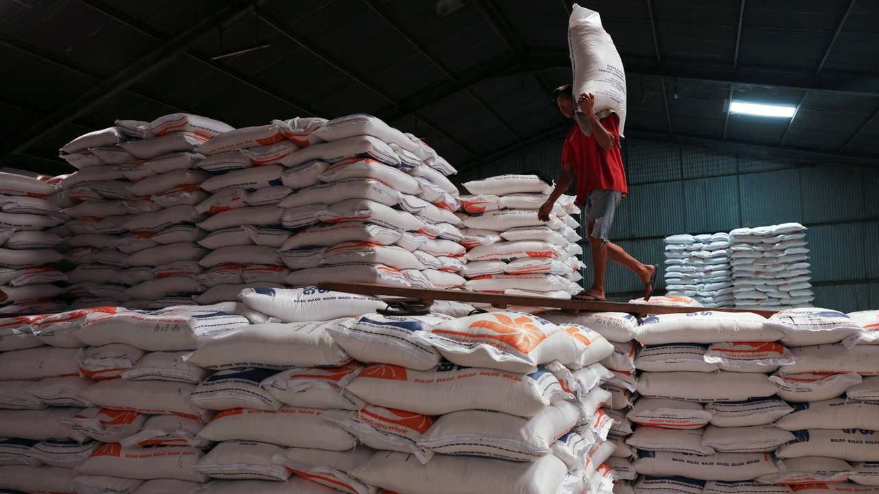 A worker carries a sack of rice at the warehouse in Jakarta