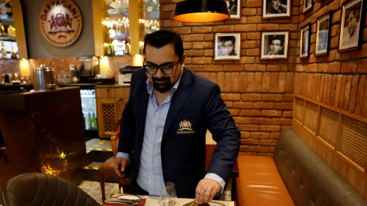 Amit Bagga, CEO of Daryaganj restaurant, shows a freshly prepared butter chicken dish and the lentil dish Dal Makhani, inside Daryaganj restaurant at a mall, in Noida