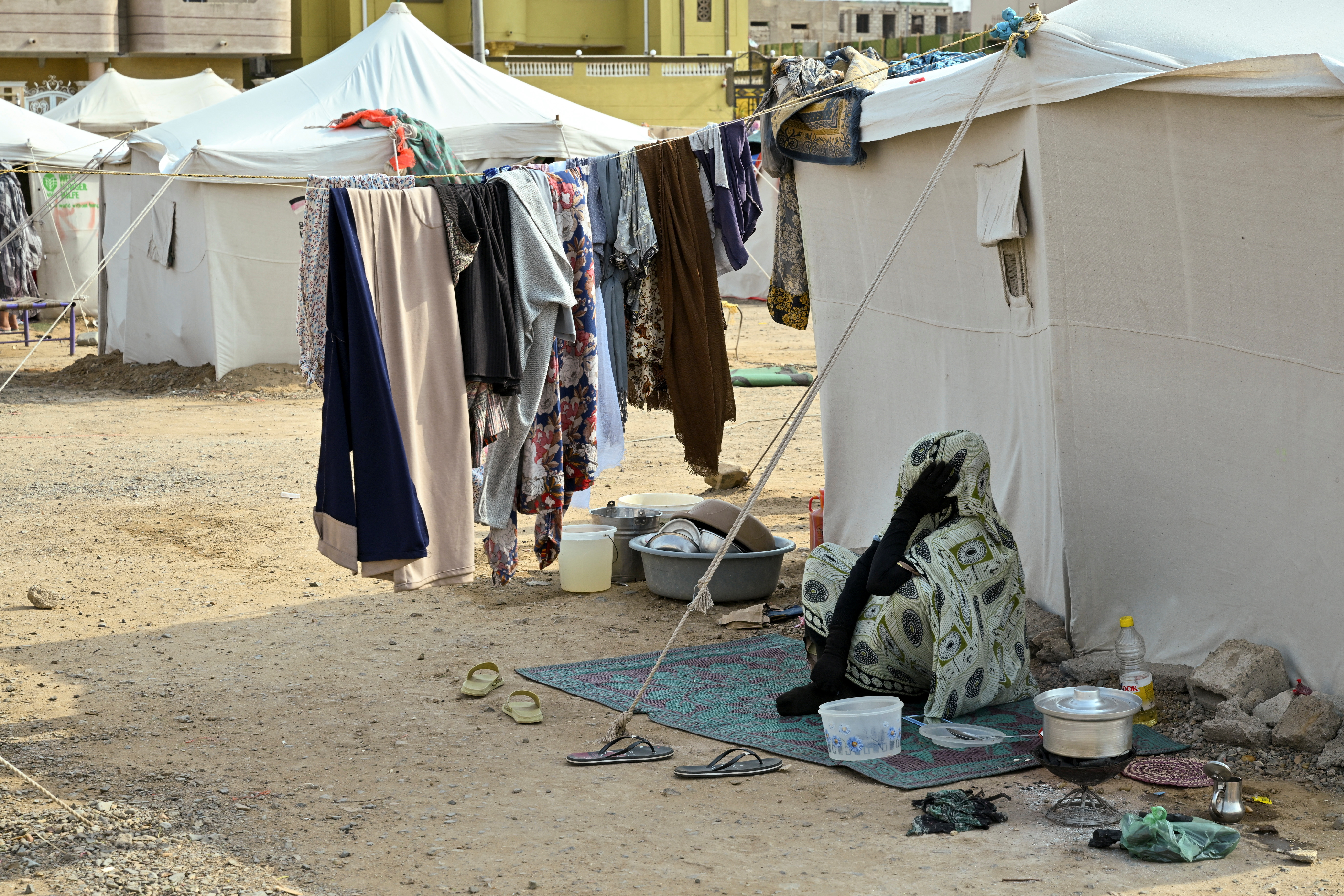 A displaced woman sits outside at a school turned into a shelter, in Port Sudan
