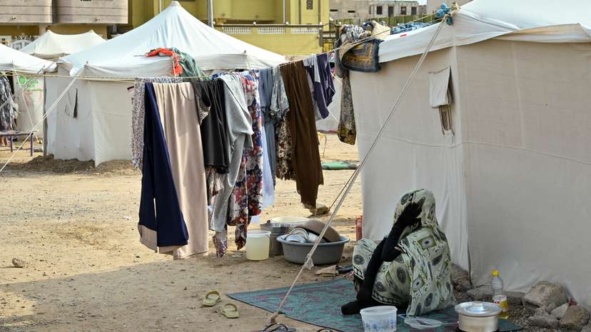 A displaced woman sits outside at a school turned into a shelter, in Port Sudan