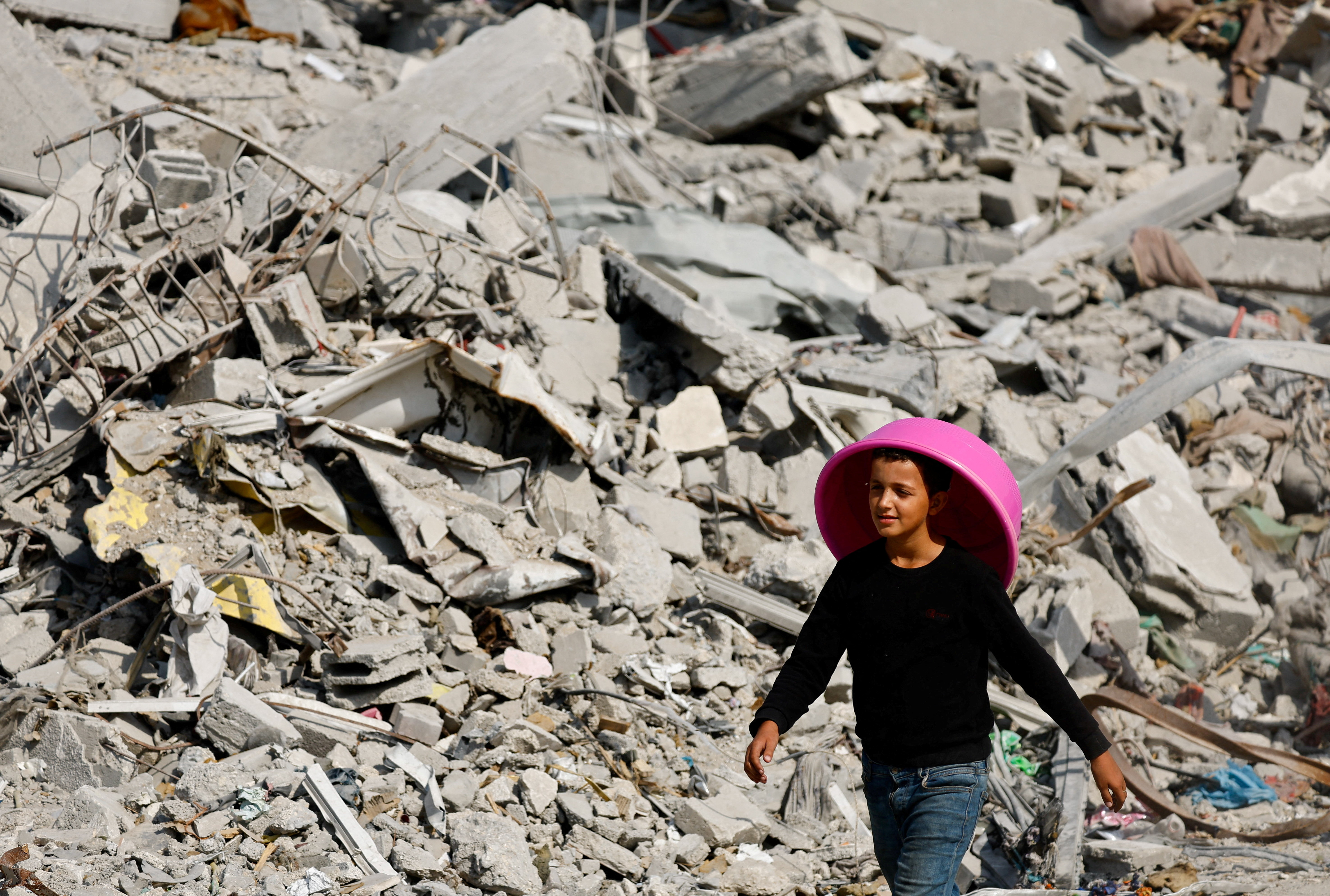 FILE PHOTO: A Palestinian youth walks past the rubble of destroyed buildings, amid a ceasefire between Israel and Hamas, in Gaza City