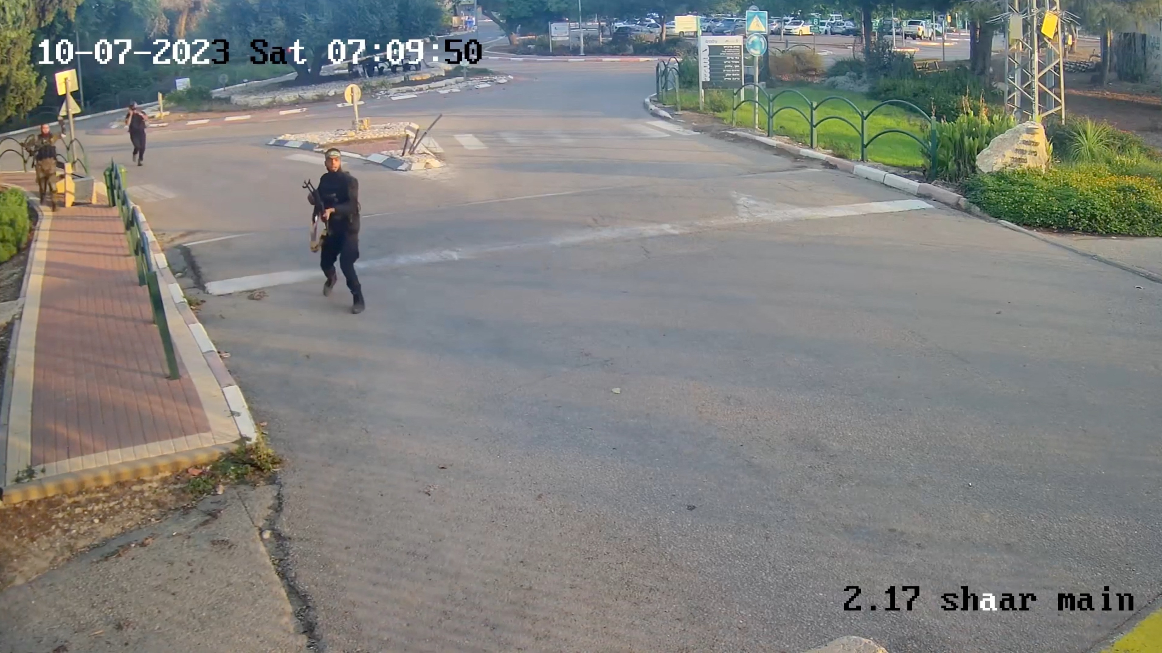 An armed man runs aiming his gun during the October 7 attack by Hamas in  Kibbutz Alumim