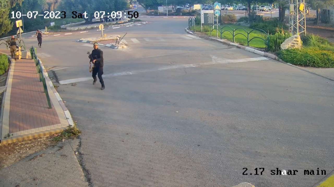 An armed man runs aiming his gun during the October 7 attack by Hamas in Kibbutz Alumim