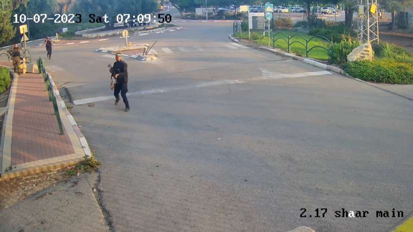 An armed man runs aiming his gun during the October 7 attack by Hamas in Kibbutz Alumim