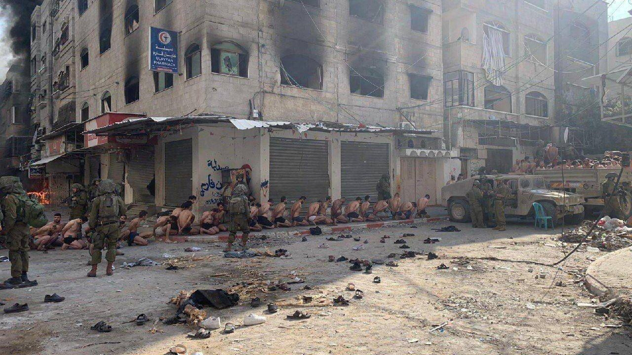 Captured and detained Palestinians sit on a street in Beit Lahia