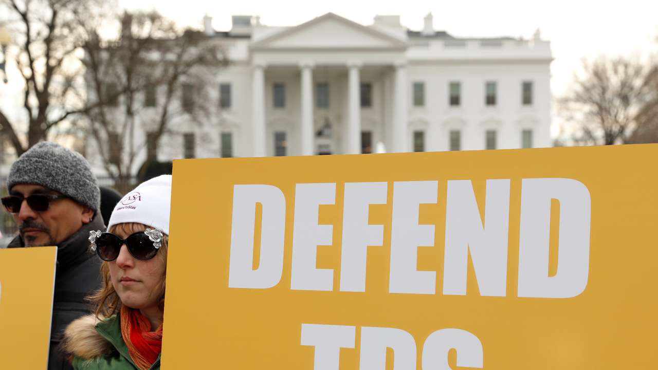 Demonstrators hold signs advocating for Temporary Protected Status