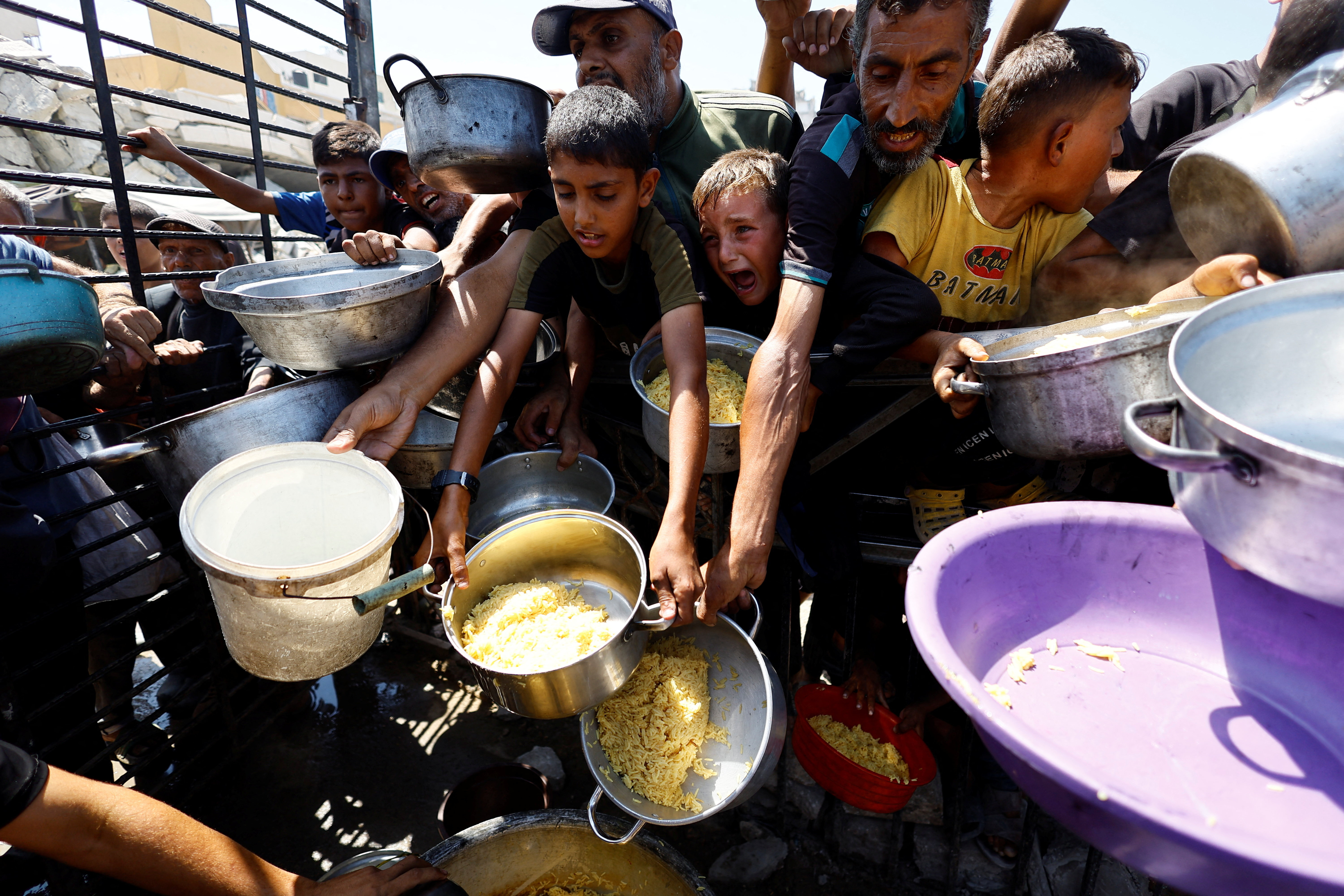 Palestinians wait to receive food from a charity kitchen, in Gaza City